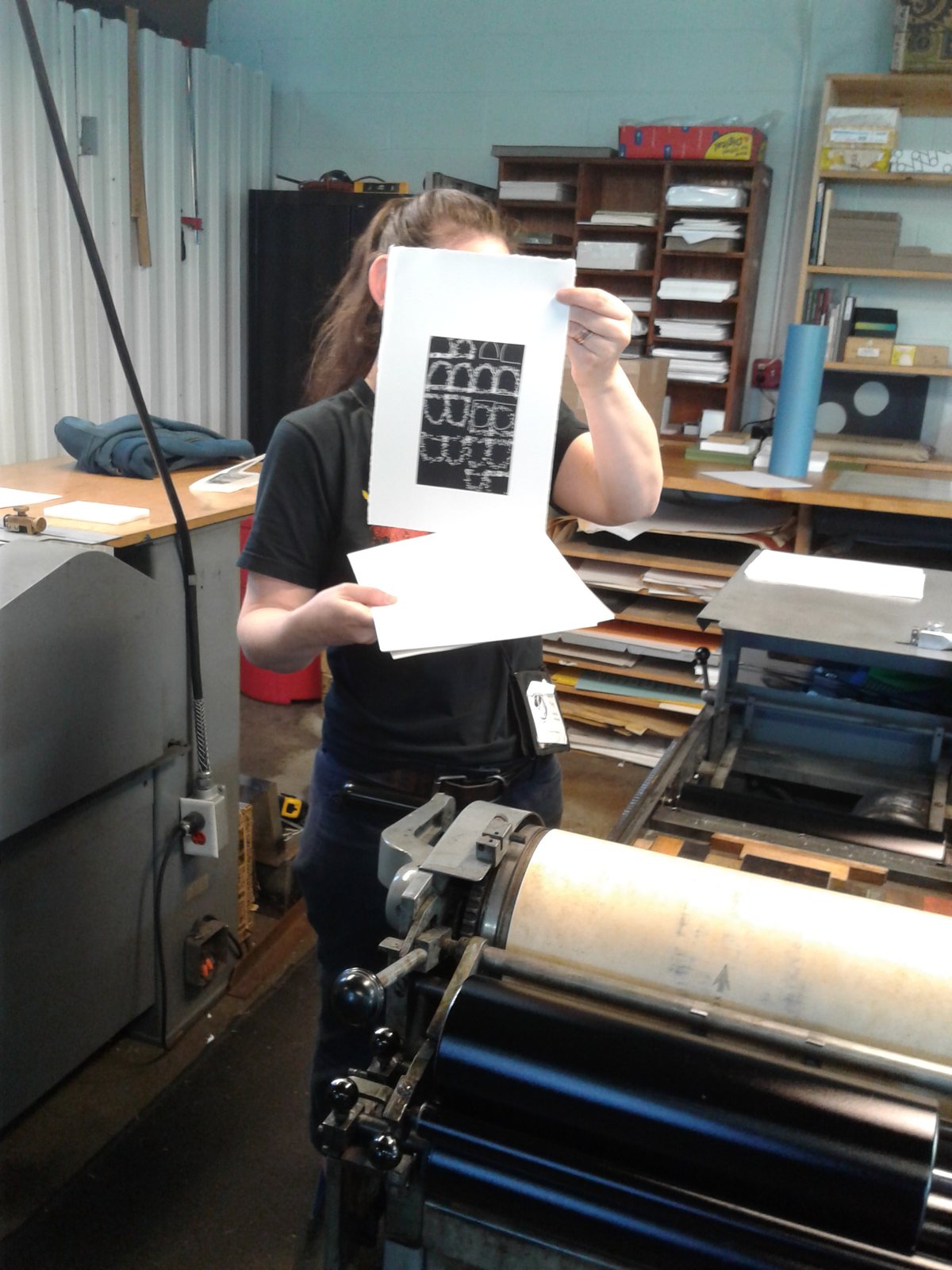 A workshop participant holding a print above a printing press