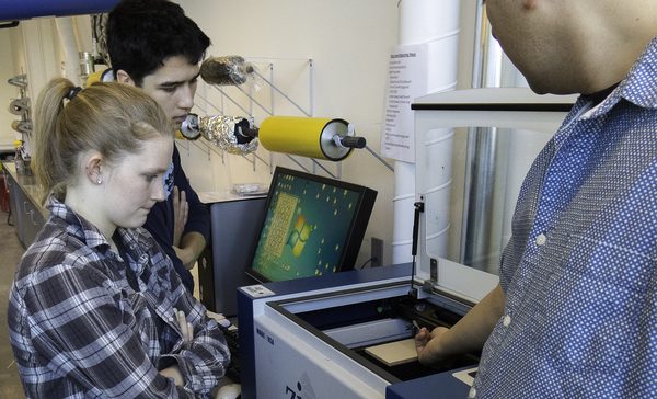Participants gathered around a laser cutter during a printmaking workshop