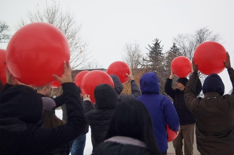 Workshop participants holding large red balloons outdoors during a sound exercise