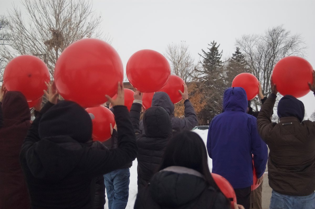 Workshop participants holding large red balloons outdoors during a sound exercise